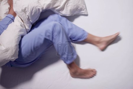 Mann mit RLS - Restless Legs Syndrom. Schlafen im Bett