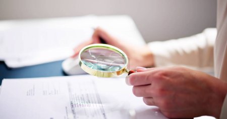 Photo for Corporate Auditor Using Magnifying Glass For Tax Fraud Audit - Royalty Free Image