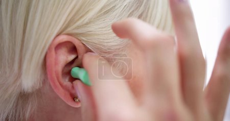 Téléchargez les photos : Femme mettre bouchon d'oreille dans son oreille dans le lit - en image libre de droit