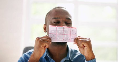 Foto de Hombre Africano Besando Boleto de Apuesta. Tarjeta de juego de lotería - Imagen libre de derechos