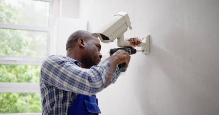 Photo for Close-up Of Technician Adjusting CCTV Camera On Wall - Royalty Free Image