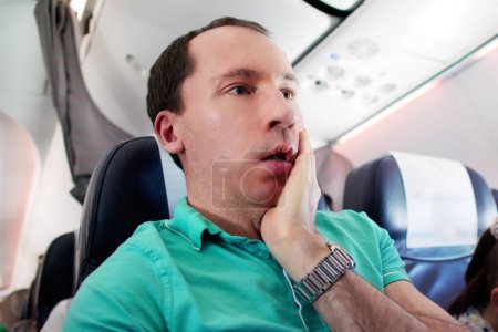 Foto de Joven hombre teniendo ataque de ansiedad en avión - Imagen libre de derechos