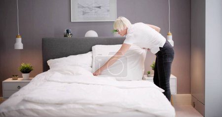 Photo for Young Female Housekeeper Changing Bedding In Hotel Room - Royalty Free Image