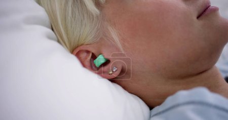 Téléchargez les photos : Femme dormant avec des bouchons d'oreilles dans ses oreilles au lit - en image libre de droit