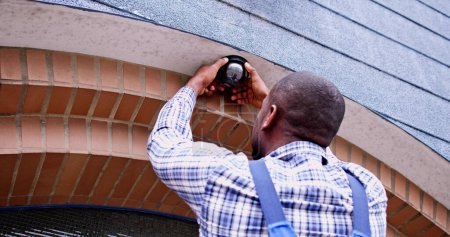 Foto de Instalador de cámara CCTV Handyman afroamericano en escalera - Imagen libre de derechos