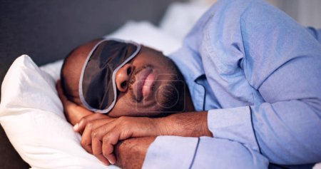 Téléchargez les photos : Jeune homme africain dormant avec masque de sommeil - en image libre de droit
