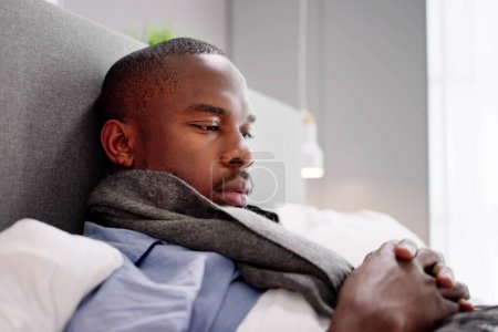 Téléchargez les photos : Malade homme africain au lit avec douleur - en image libre de droit