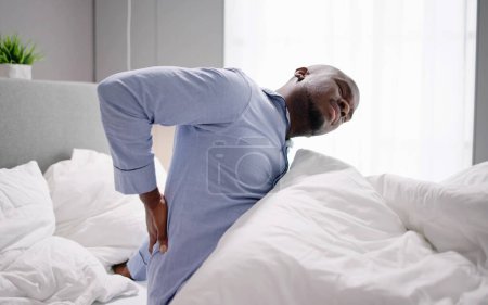 Photo for Man Sitting On Bed Suffering From Back Pain - Royalty Free Image