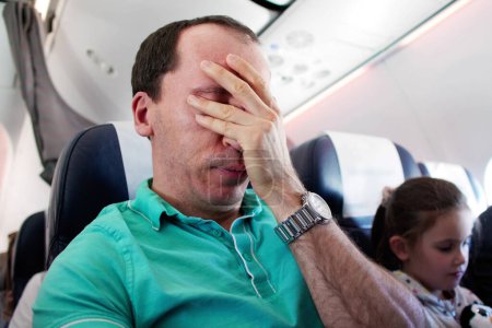 Foto de Joven hombre teniendo ataque de ansiedad en avión - Imagen libre de derechos