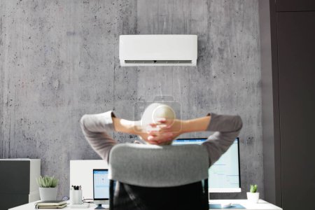 Téléchargez les photos : Femme d'affaires détendue bénéficiant du refroidissement du climatiseur dans le bureau - en image libre de droit