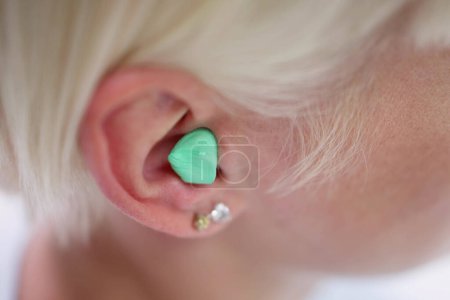 Photo for Woman Putting Earplug Into Her Ear In Bed - Royalty Free Image