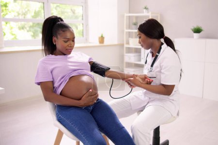 Téléchargez les photos : Gros plan du médecin féminin mesurant la pression artérielle de la femme enceinte en clinique - en image libre de droit