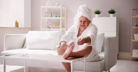 Photo for Funny Man Relaxing In Bathrobe Doing Spa Pedicure At Home - Royalty Free Image