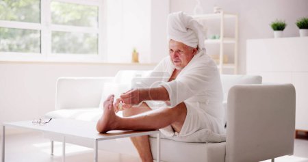 Foto de Hombre divertido relajarse en el albornoz haciendo pedicura spa en casa - Imagen libre de derechos