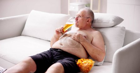 Photo for Overeating Junk Food, Drinking Beer And Watching TV - Royalty Free Image