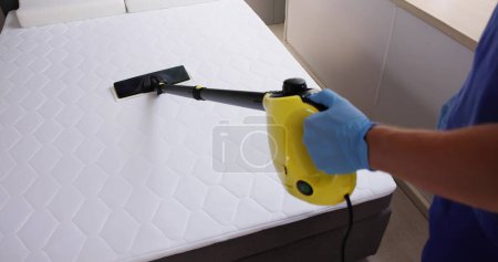 Foto de Colchón de cama de limpieza con máquina de vapor. Tratamiento de chinches de cama - Imagen libre de derechos