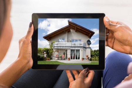 Foto de Primer plano de una pareja mirando la casa en la tableta digital - Imagen libre de derechos