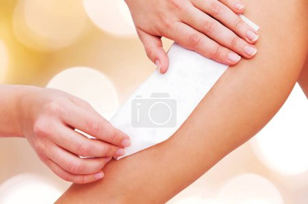 Photo for Close-up Of A Therapist Waxing Female Customer's Leg With Wax Strip - Royalty Free Image