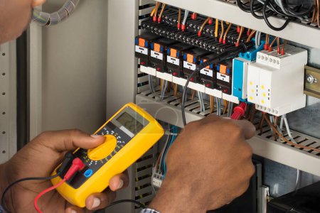Photo for Close-up Of Male Electrician Checking Fuse Box With Multimeter - Royalty Free Image