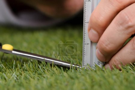 Photo for Close-up Of A Man Using Measuring Scale While Cutting Grass With Scissors - Royalty Free Image