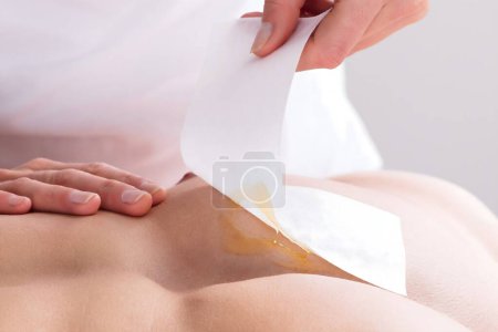 Photo for Close-up Of A Woman Waxing Man's Chest With Wax Strip - Royalty Free Image
