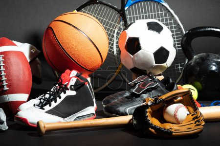 Téléchargez les photos : Variété de balles de sport et d'équipement devant la surface noire - en image libre de droit
