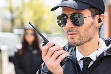 Photo for Portrait Of A Male Security Guard Talking On Walkie Talkie - Royalty Free Image