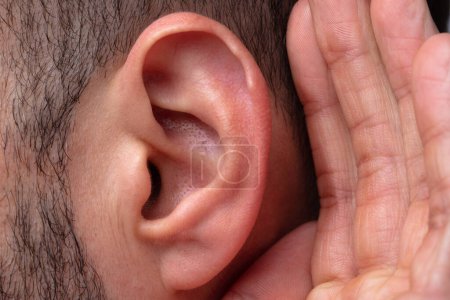 Téléchargez les photos : Gros plan d'un homme essayant d'entendre avec la main sur l'oreille - en image libre de droit