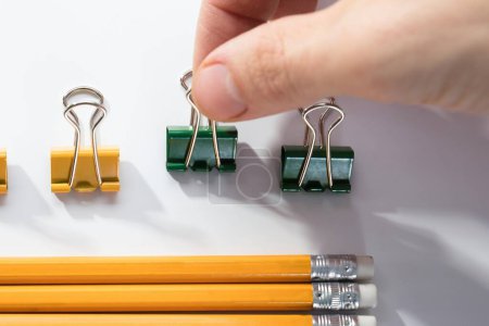 Foto de Dedo de la persona Arreglando los lápices con fila de alfileres de goma y pluma sobre fondo blanco - Imagen libre de derechos