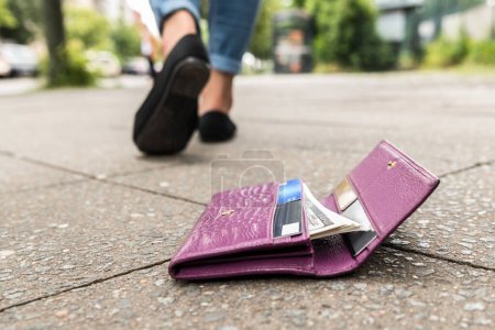 Téléchargez les photos : Femme marchant après avoir perdu son portefeuille sur la rue - en image libre de droit