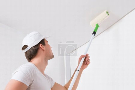 Photo for Young Painter In White Uniform Painting With Paint Roller On Wall - Royalty Free Image