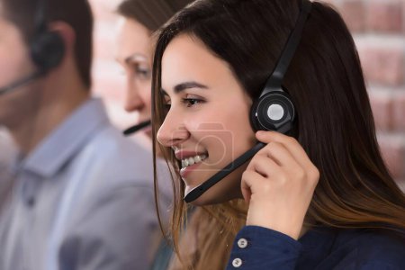 Foto de Agente de servicio al cliente femenino positivo con auriculares trabajando en un centro de llamadas - Imagen libre de derechos