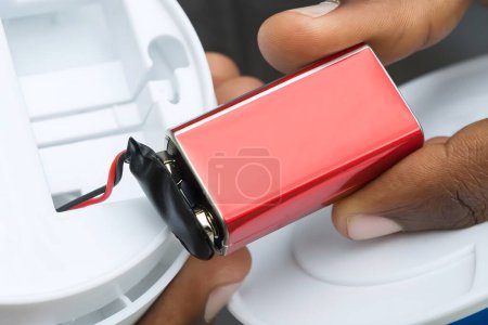Foto de Primer plano de las manos del electricista que quita la batería del detector de humo - Imagen libre de derechos