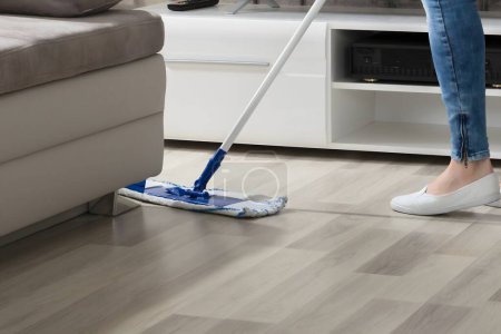 Photo for Happy Young Woman Cleaning The Hardwood Floor With Mop In Living Room - Royalty Free Image
