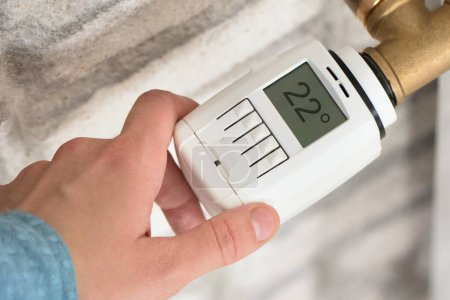 Téléchargez les photos : La main d'une personne ajustant la température sur le thermostat du radiateur - en image libre de droit