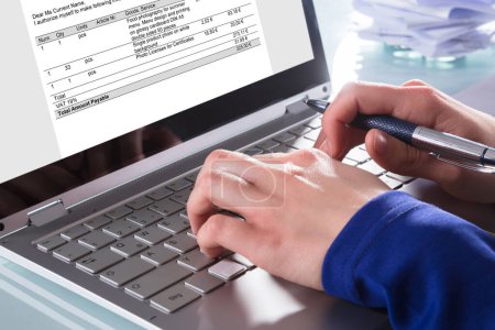 Téléchargez les photos : Gros plan de la main d'un homme d'affaires analysant la facture sur un ordinateur portable au travail - en image libre de droit