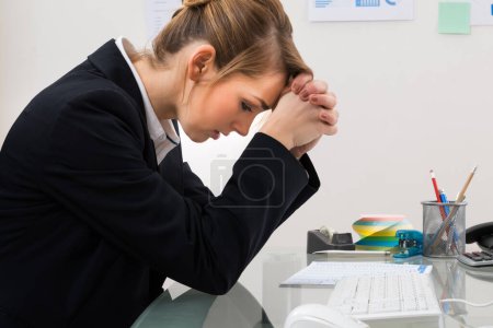 Photo for Stressed Young Businesswoman Sitting At Desk In Office - Royalty Free Image