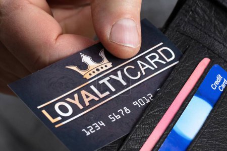 Foto de Primer plano de la mano de una persona que quita la tarjeta de lealtad negra de la billetera - Imagen libre de derechos