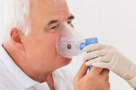 Téléchargez les photos : Médecin féminin regardant le patient masculin âgé inhalant par masque à oxygène - en image libre de droit