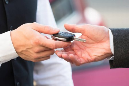 Photo for Close-up Of Valet's Hand Giving Car Key To Businessperson - Royalty Free Image