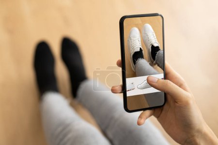 Photo for Woman Trying Virtual Sneakers In Shop Or Store AR App - Royalty Free Image