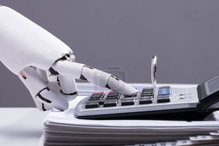 Foto de Primer plano de una mano robótica calculando facturas utilizando la calculadora en la oficina - Imagen libre de derechos