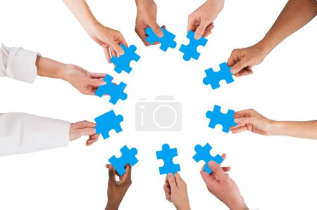 Photo for Directly above shot of medical team holding blue jigsaw pieces in huddle against white background - Royalty Free Image