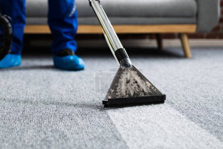 Photo for Janitor Cleaning Carpet With Vacuum Cleaner At Home - Royalty Free Image