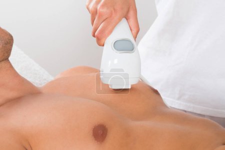 Téléchargez les photos : Femme esthéticienne donnant épilation laser sur la poitrine de l'homme - en image libre de droit