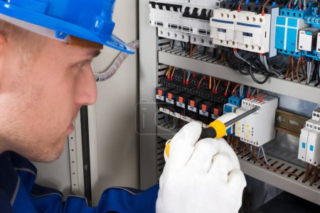 Photo for Male Electrician Working On Fusebox With Screwdriver - Royalty Free Image