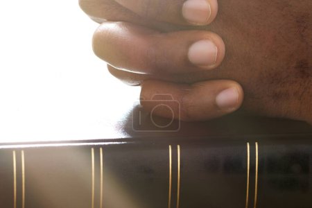 Foto de La luz del sol cae sobre la mano del hombre sobre el libro sagrado de la Biblia - Imagen libre de derechos