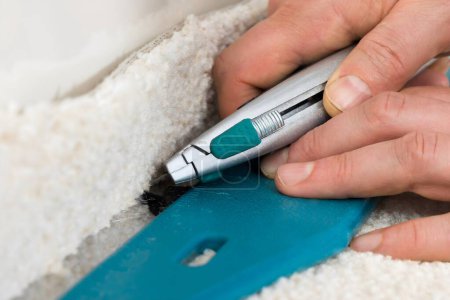 Photo for Close-up Of A Craftsman Cutting Carpet With Cutter - Royalty Free Image