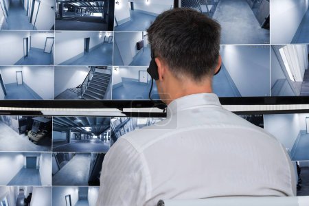 Téléchargez les photos : Vue arrière d'un opérateur de système de sécurité regardant des images de vidéosurveillance au bureau - en image libre de droit