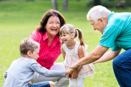 Happy Old Grandparents Having Fun With Grandchildren  In Park